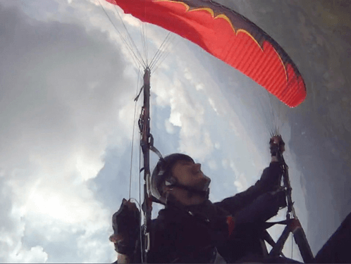 Piloto realiza um McTwist para a direita no parapente vermelho abordo